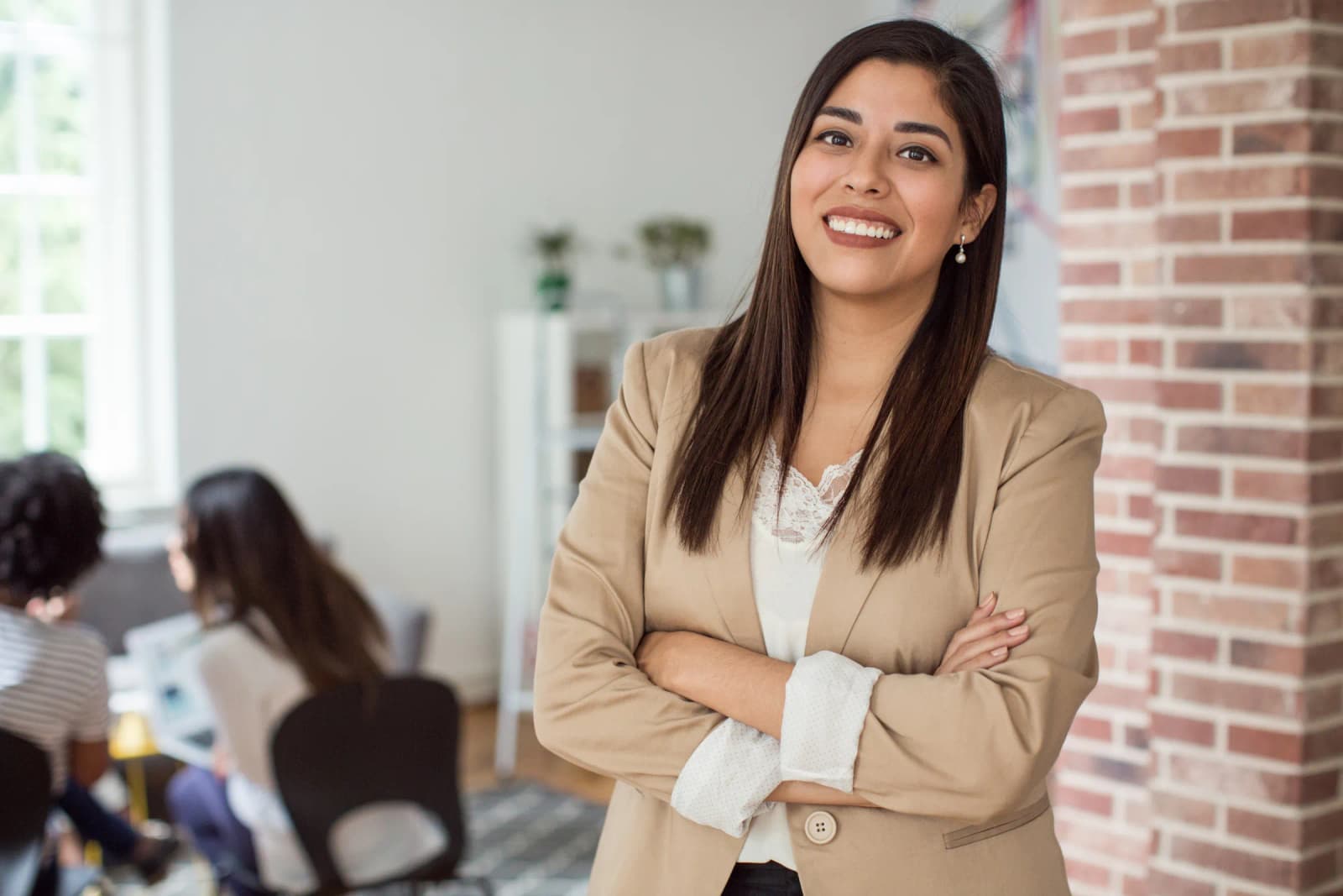 A smiling professional standing in a brick-walled office