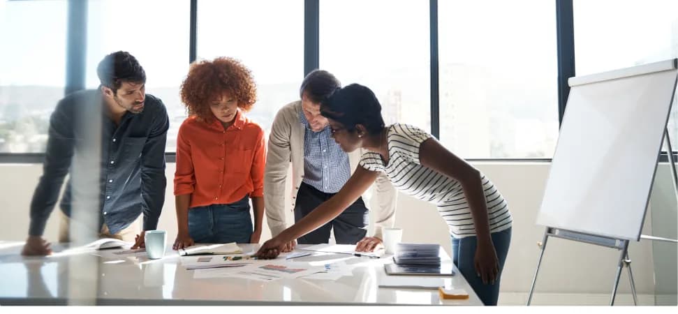A team gathered around a table in a meeting room beside a whiteboard
