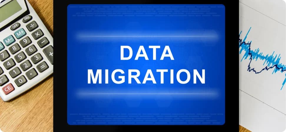 A monitor displaying the words Data Migration beside a calculator and a chart